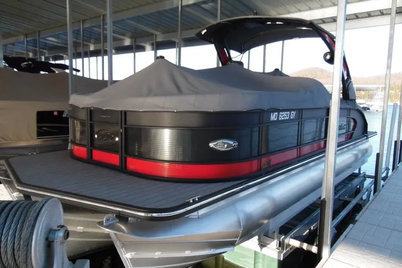 Slide: The Image of 2023 Manitou 25 XT RFX pontoon boat docked under a covered marina. - 23