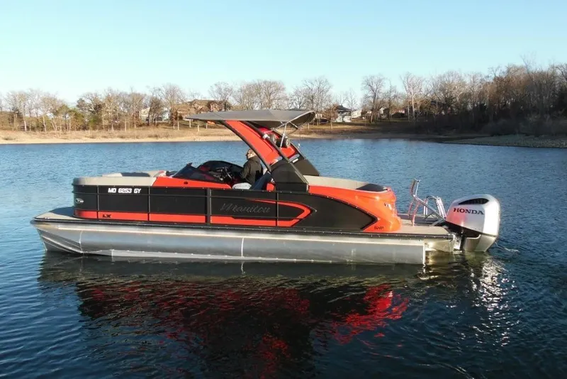 Slide: The Image of 2023 Manitou 25 XT RFX pontoon boat on a calm lake with Honda outboard. - 6