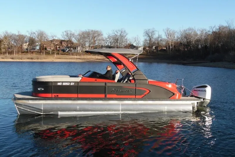 Slide: The Image of 2023 Manitou 25 XT RFX pontoon boat on a calm lake with Honda outboard. - 7