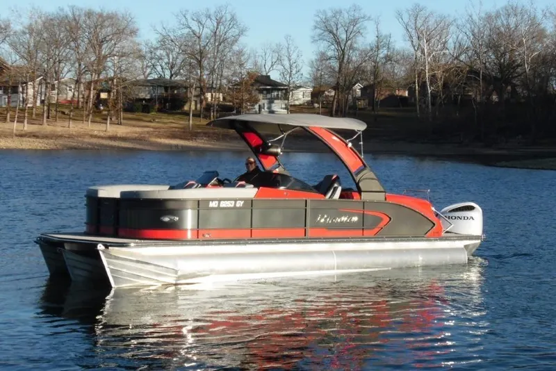 Slide: The Image of 2023 Manitou 25 XT RFX pontoon boat on a calm lake with trees in the background. - 9