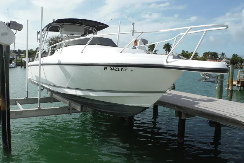 The Image of 1999 Intrepid 289 Center Console boat docked on a lift in a marina. - 1