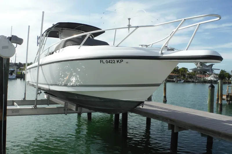 Slide: The Image of 1999 Intrepid 289 Center Console boat on lift, docked by waterfront. - 60