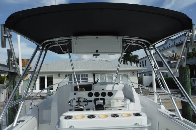 Slide: The Image of 1999 Intrepid 289 Center Console boat with T-top and steering console, docked near a house. - 9