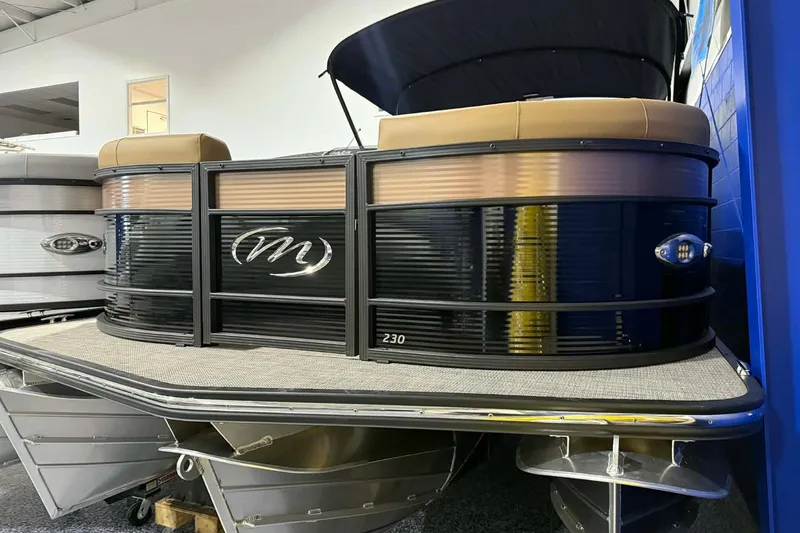 The Image of 2026 Manitou Encore VP 230 pontoon boat with sleek black and tan design in showroom. - 0