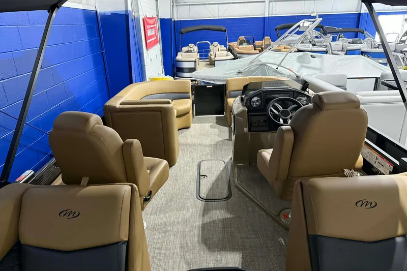 Slide: The Image of 2026 Manitou Encore VP 230 pontoon boat interior with tan seating and steering console. - 17