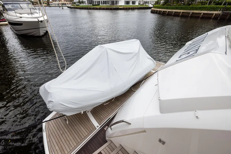 Slide: The Image of 2019 Sunseeker 76 yacht with covered equipment on deck, docked by waterfront homes. - 132