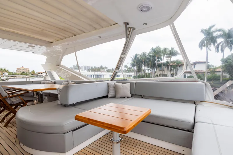 Slide: The Image of Luxurious 2019 Sunseeker 76 yacht interior with elegant seating and wooden tables, docked near palm trees. - 16