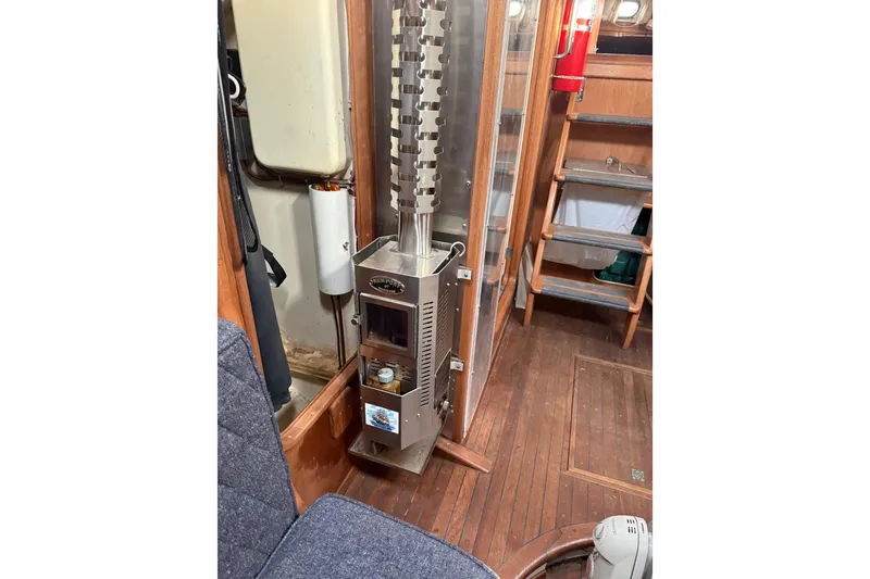 Slide: The Image of Cozy boat interior with a compact stove, wooden flooring, and ladder. Custom model 46, 1990. - 13