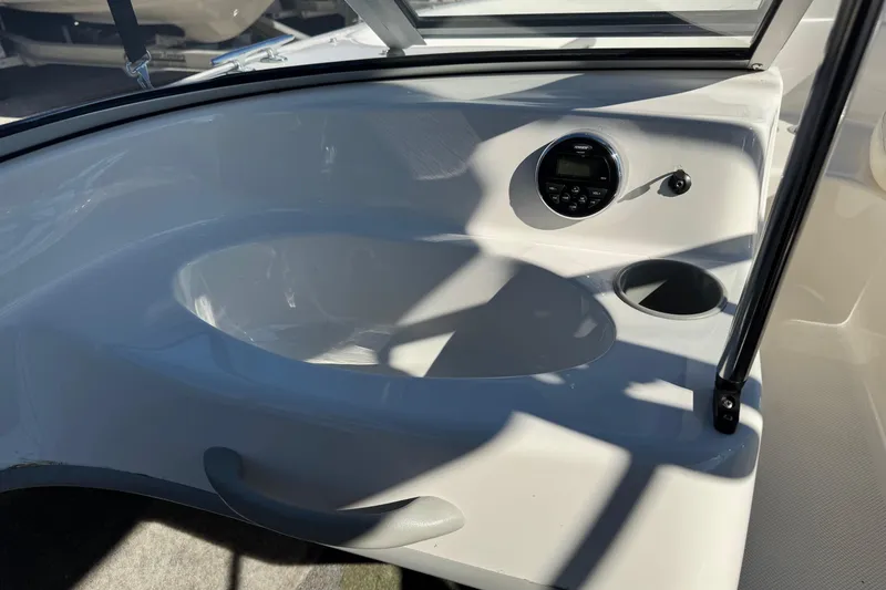 Slide: The Image of 2013 Bayliner 160 Bowrider dashboard with stereo and cup holder in sunlight. - 12