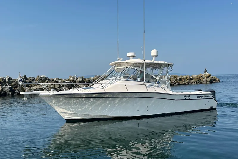 Slide: The Image of 2008 Grady White Express boat on calm water near rocky shoreline. - 1