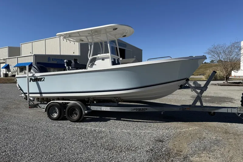 The Image of 2026 Parker 230 Coastal Elite boat on trailer, parked outdoors near industrial buildings. - 0