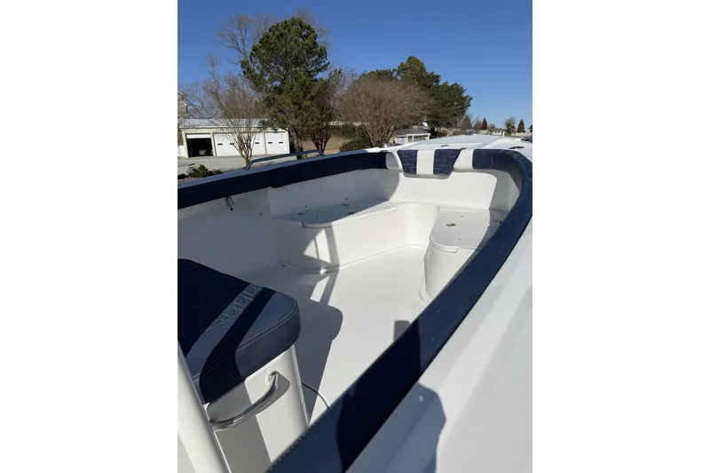 Slide: The Image of 2026 Parker 230 Coastal Elite boat interior with seating and storage, under clear blue sky. - 5