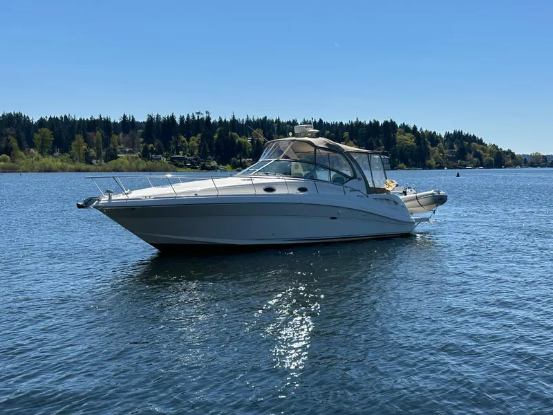 The Image of 2004 Sea Ray 340 Sundancer boat on a calm lake under clear blue sky. - 0