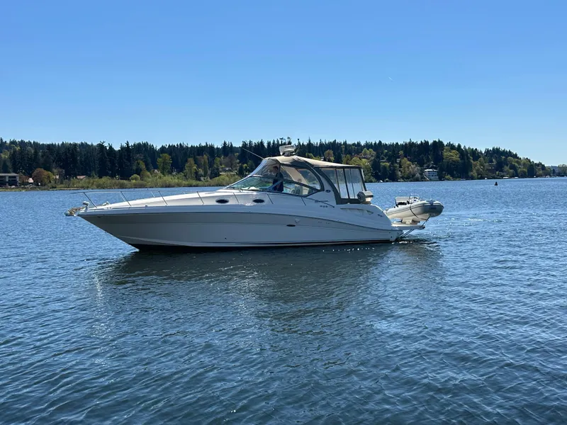 Slide: The Image of 2004 Sea Ray 340 Sundancer cruising on a serene lake under a clear blue sky. - 4