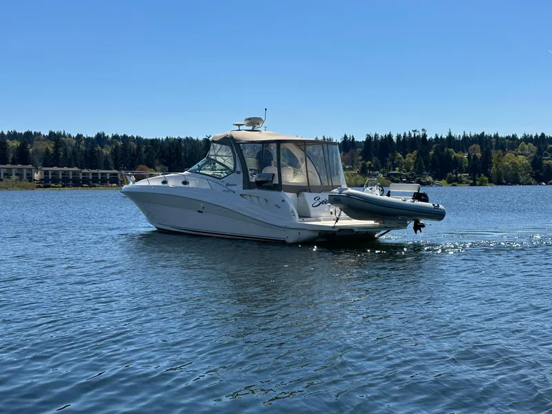 Slide: The Image of 2004 Sea Ray 340 Sundancer cruising on a serene lake under a clear blue sky. - 5