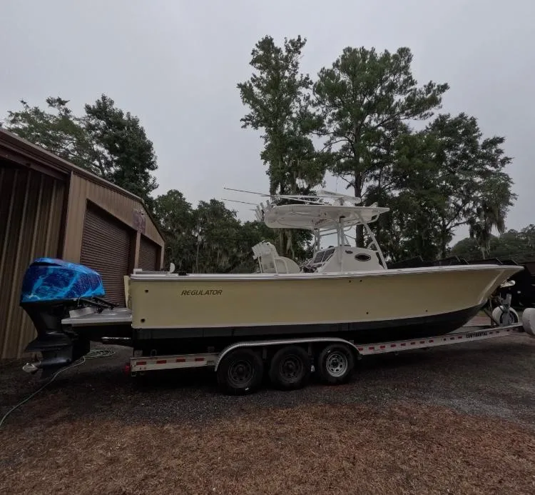 Slide: The Image of 2013 Regulator 34 Center Console boat on trailer, parked near trees. - 10
