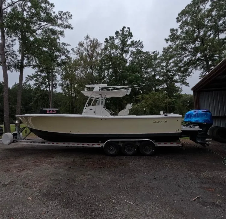Slide: The Image of 2013 Regulator 34 Center Console boat on trailer, surrounded by trees. - 2