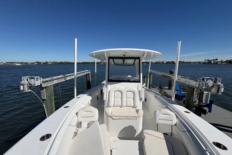 Slide: The Image of 2018 Sea Hunt Gamefish 30 boat with forward seating, docked by a scenic waterfront. - 18
