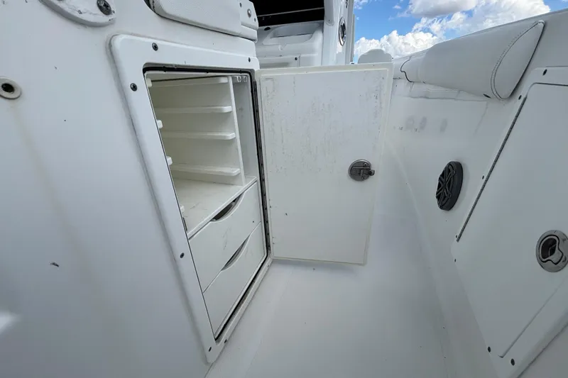 Slide: The Image of 2018 Sea Hunt Gamefish 30 Forward Seating storage compartment with open door, showcasing shelves and drawers. - 35