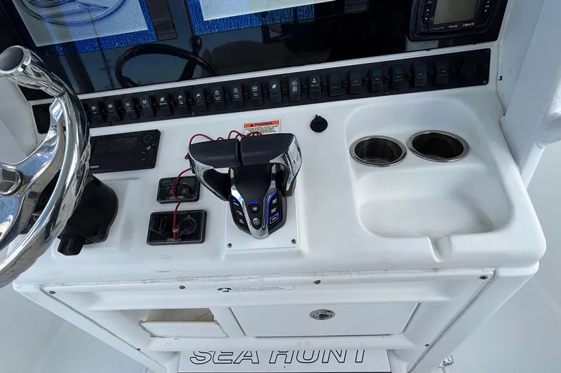 Slide: The Image of 2018 Sea Hunt Gamefish 30 helm with steering wheel, controls, and cup holders. - 64