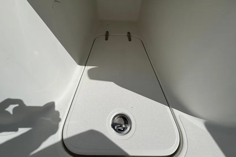 Slide: The Image of 2018 Sea Hunt Gamefish 30 Forward Seating storage compartment, white interior, sunlight shadow. - 85