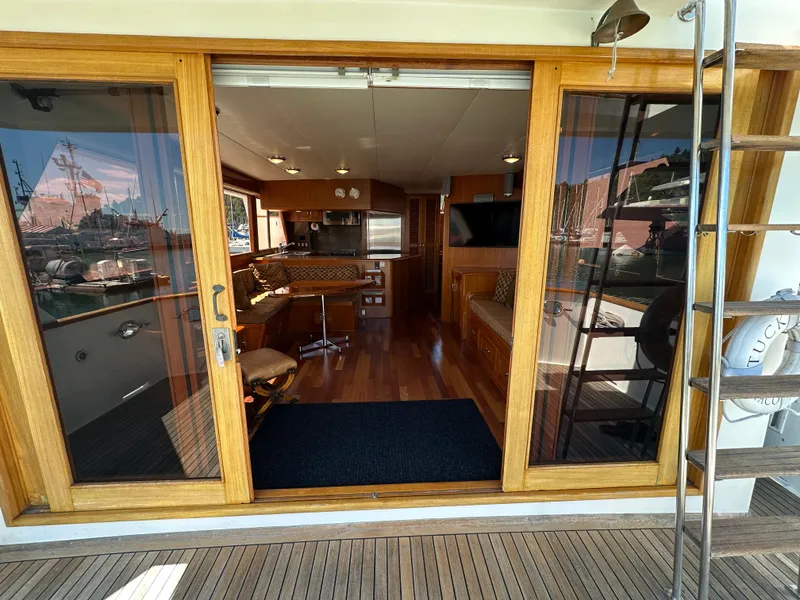 Slide: The Image of 1985 Ocean Alexander Pilothouse interior with wooden flooring, kitchen, and seating area. - 32