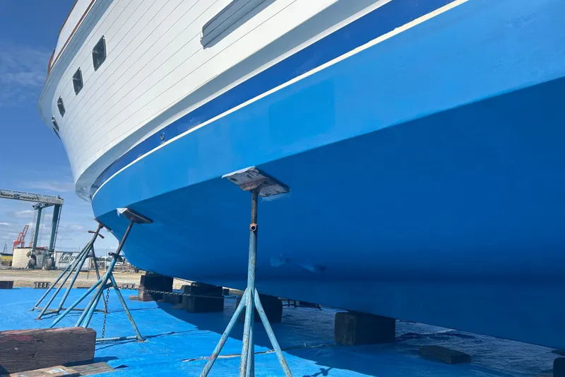 Slide: The Image of 1985 Ocean Alexander Pilothouse yacht on stands, blue hull, shipyard setting. - 105