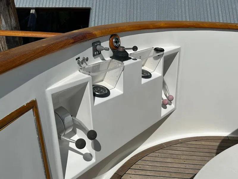 Slide: The Image of 1985 Ocean Alexander Pilothouse helm controls with wooden accents and nautical instruments. - 14