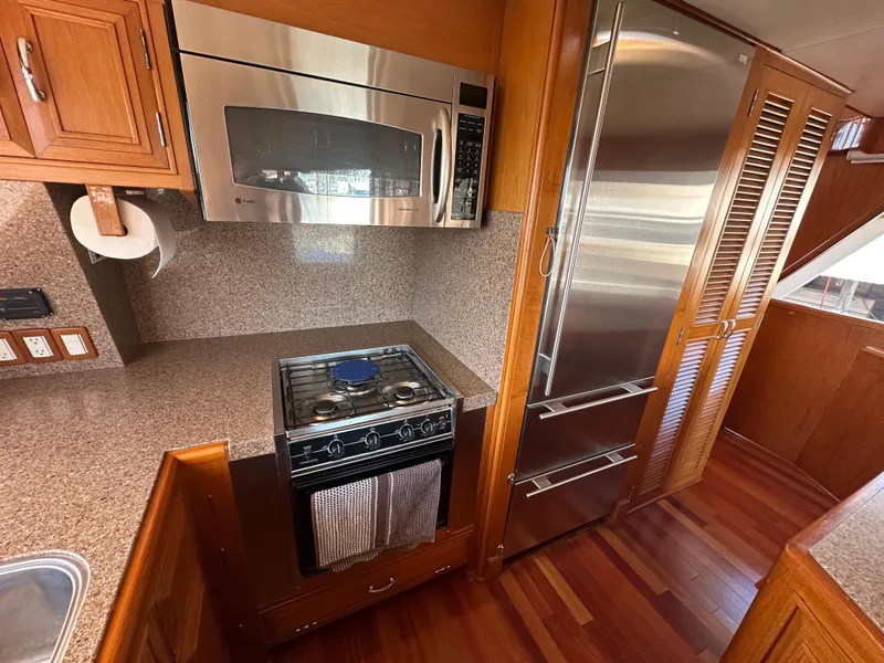 Slide: The Image of 1985 Ocean Alexander Pilothouse kitchen with stainless steel appliances and wooden cabinetry. - 43