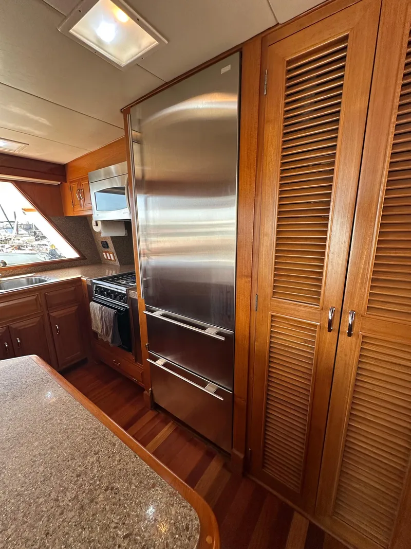 Slide: The Image of 1985 Ocean Alexander Pilothouse kitchen with stainless steel appliances and wooden cabinetry. - 45
