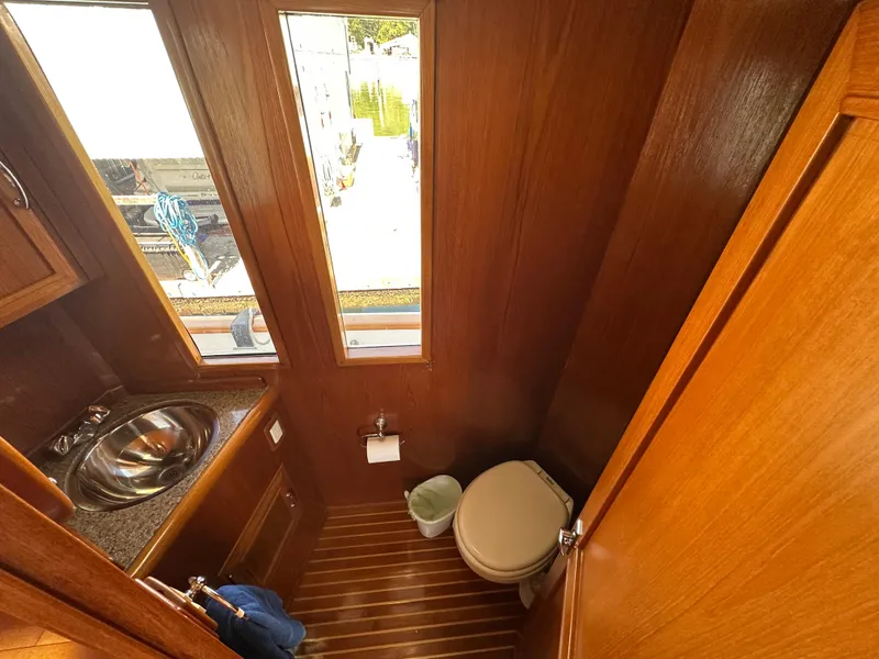 Slide: The Image of 1985 Ocean Alexander Pilothouse bathroom with wooden interior, sink, and toilet. - 49