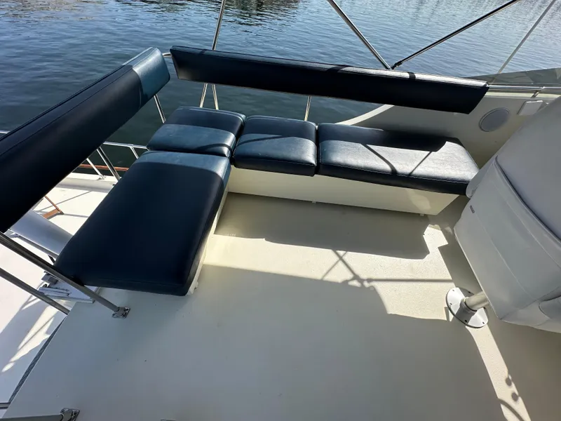 Slide: The Image of 1982 Tollycraft Tri Cabin boat seating area with blue cushions, overlooking water. - 21