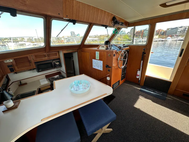 Slide: The Image of 1982 Tollycraft Tri Cabin interior with helm, dining area, and waterfront view. - 29