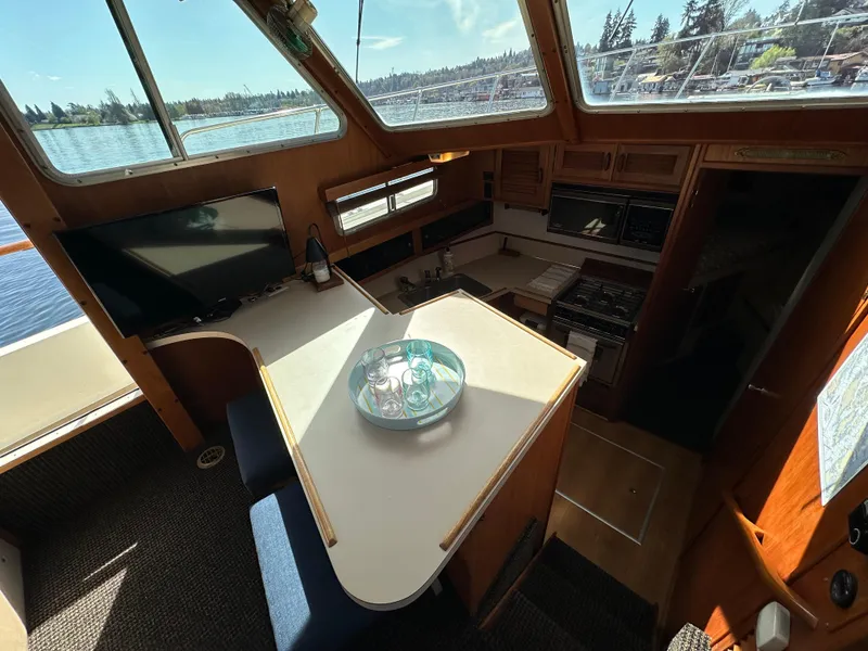 Slide: The Image of 1982 Tollycraft Tri Cabin interior with dining area, kitchen, and scenic window views. - 35