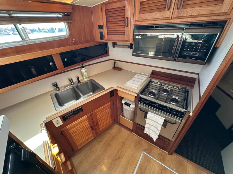 Slide: The Image of 1982 Tollycraft Tri Cabin kitchen with stove, sink, and wooden cabinetry. - 36