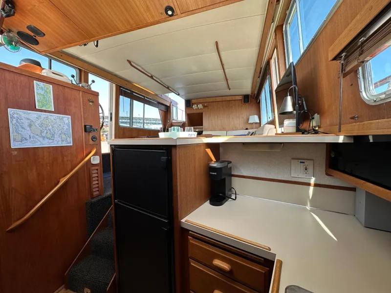 Slide: The Image of 1982 Tollycraft Tri Cabin interior with kitchenette, wooden cabinetry, and natural light. - 39