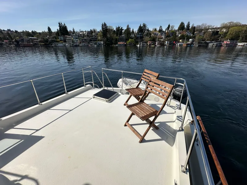 Slide: The Image of 1982 Tollycraft Tri Cabin boat deck with wooden chairs, overlooking calm water and shoreline. - 12