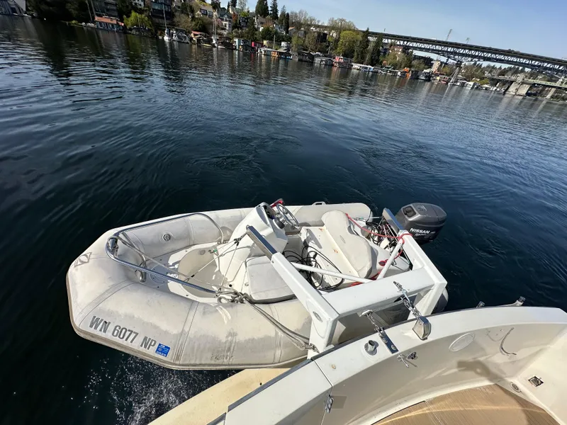 Slide: The Image of 1982 Tollycraft Tri Cabin with inflatable dinghy on calm water near a bridge. - 13