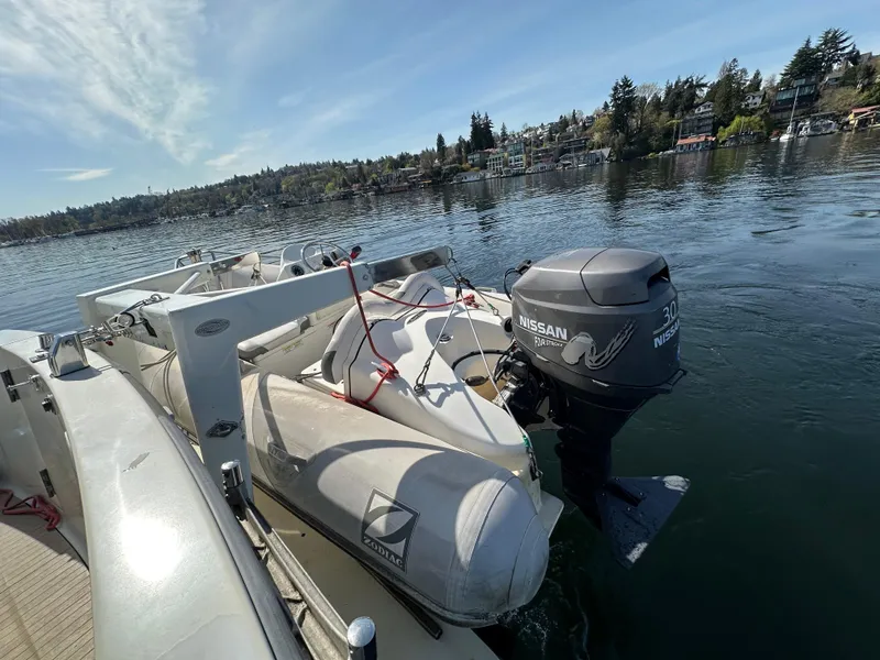Slide: The Image of 1982 Tollycraft Tri Cabin with dinghy and Nissan outboard motor on a calm lake. - 14