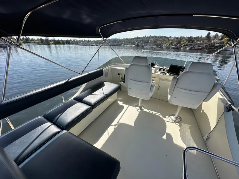 Slide: The Image of 1982 Tollycraft Tri Cabin boat interior with seating and helm, overlooking a serene lake. - 20