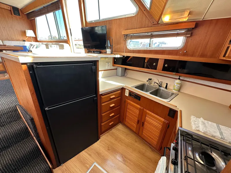 Slide: The Image of 1982 Tollycraft Tri Cabin kitchen with wood cabinetry, black fridge, and dual sink. - 37