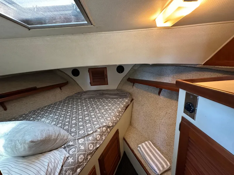 Slide: The Image of 1982 Tollycraft Tri Cabin interior with cozy bed, wooden accents, and soft lighting. - 45