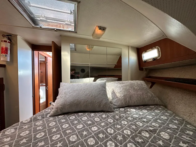 Slide: The Image of 1982 Tollycraft Tri Cabin bedroom with patterned bedding, skylight, and wooden accents. - 46