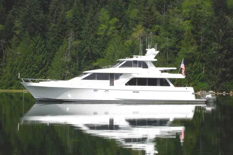 Slide: The Image of Luxury 2001 Nordlund Enclosed Command Bridge yacht on calm water, surrounded by lush forest. - 40