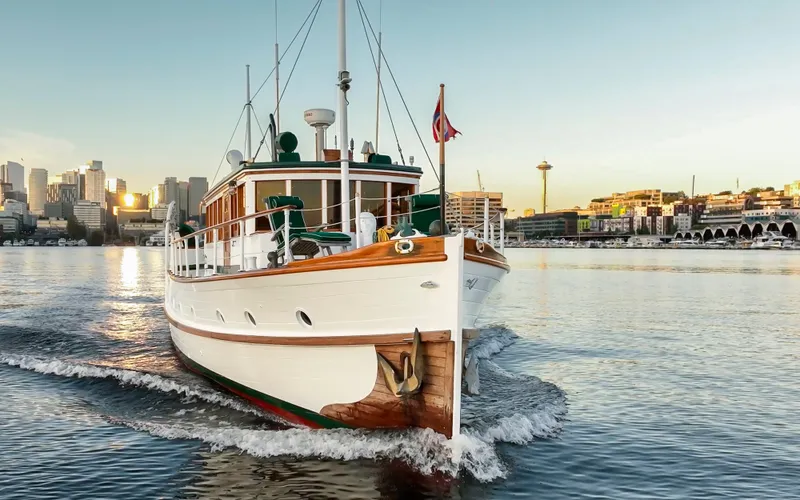 Slide: The Image of Vintage 1931 Boeing Custom yacht cruising near city skyline at sunset. - 9
