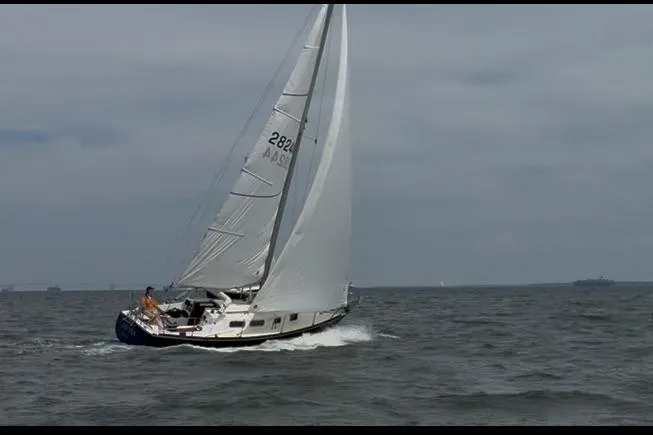 Slide: The Image of 1974 Tartan 30 sailboat navigating open waters under cloudy skies. - 1
