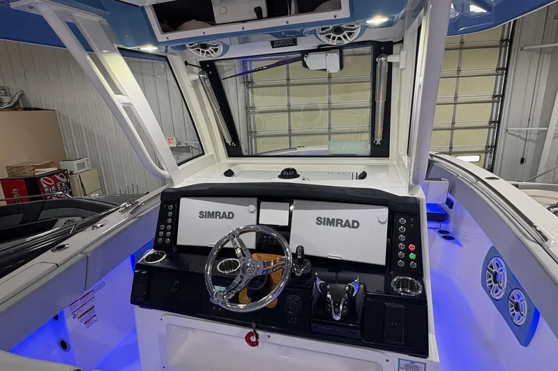 Slide: The Image of 2026 Robalo R300 Center Console boat dashboard with Simrad electronics and illuminated controls. - 7