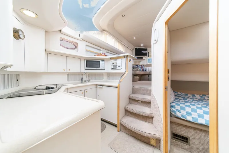 Slide: The Image of 1998 Sea Ray 420 Aft Cabin interior with kitchen, stairs, and cozy sleeping area. - 38