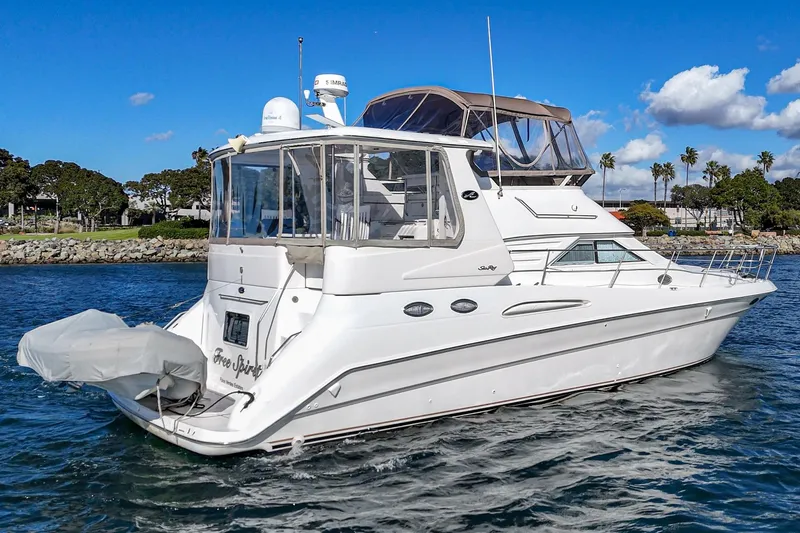 Slide: The Image of 1998 Sea Ray 420 Aft Cabin yacht on water, clear sky, coastal background. - 4