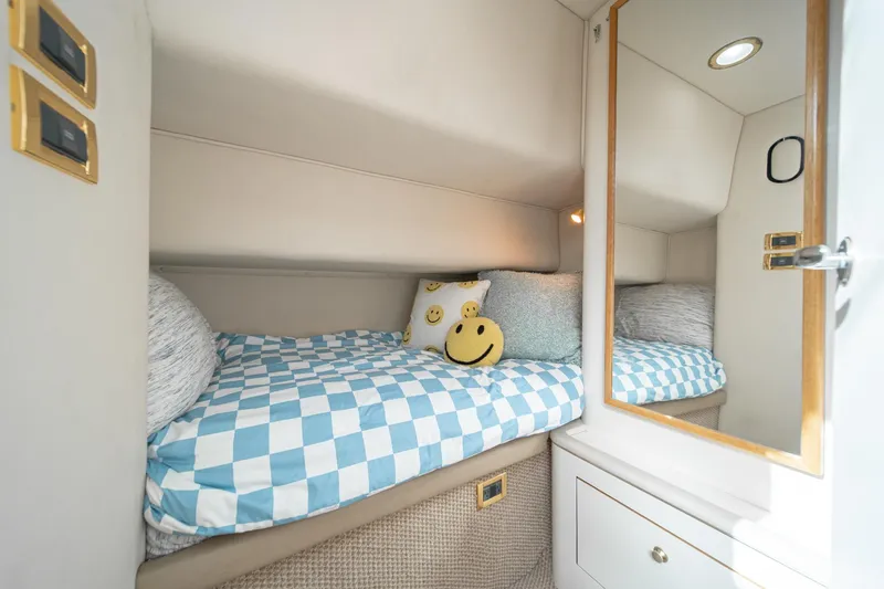 Slide: The Image of 1998 Sea Ray 420 Aft Cabin interior with cozy bed, checkered bedding, and smiley face pillow. - 40